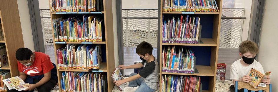 3 students sitting and reading in the library